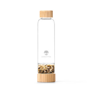Wiederverwendbare Glasflasche von Lotus Vita mit Bambusdeckel und -boden, wobei der Boden eine separate Kammer mit gold-braunen Edelsteinen enthält.